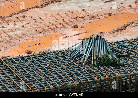 Couper les tiges et barres en acier assis sur le sol d'un chantier en attente d'être mélangé avec du béton dans les fondations des bâtiments Banque D'Images