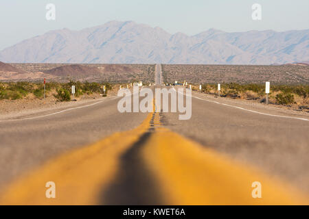 Vue panoramique horizontal Classique sans fin d'une route droite qui traverse les paysages arides de la sud-ouest des États-Unis, sur une belle journée Banque D'Images