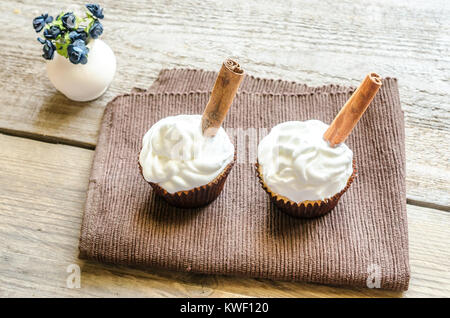 Cupcakes avec de la crème fouettée et la cannelle Banque D'Images