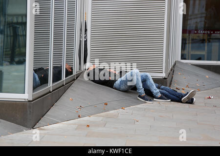 Deux hommes sans-abri dormant dehors sur un pret café à Londres, Royaume-Uni. Banque D'Images