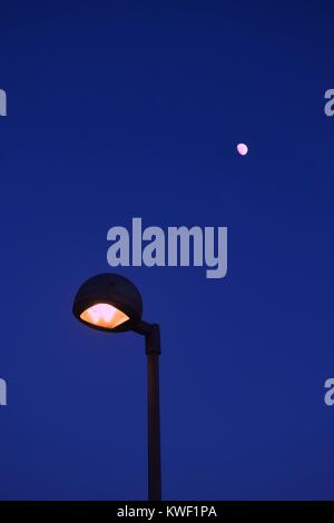 Rue moderne lampe allumée et la lune sur le ciel crépusculaire Banque D'Images