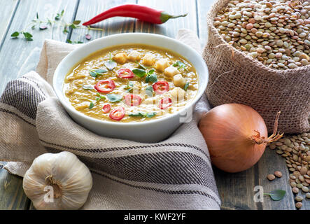 Soupe de lentilles épicée au piment, l'ail et l'oignon sur la table en bois rustique. La soupe est servie avec du chili, les croûtons et les feuilles de thym. Banque D'Images