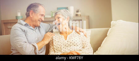 Romantic senior couple laughing while sitting on sofa Banque D'Images