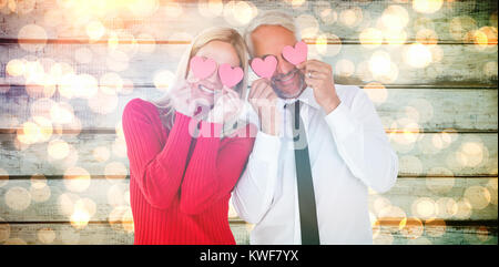 Image composite de silly couple holding cœurs sur les yeux Banque D'Images