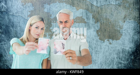 Image composite d'un couple malheureux tenant deux moitiés de déchiré photographie Banque D'Images