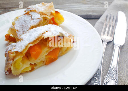 Citrouille Strudel aux pommes et aux raisins sur parchemin, menthe, fruits et légumes sur une planche en bois foncé Banque D'Images