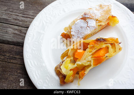 Citrouille Strudel aux pommes et aux raisins sur parchemin, menthe, fruits et légumes sur une planche en bois foncé Banque D'Images