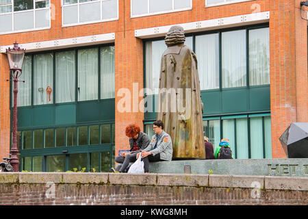 Amsterdam, Pays-Bas - 20 juin 2015 : Les gens s'asseoir près de la statue de Spinoza au bord de l'eau de canal à Amsterdam Banque D'Images