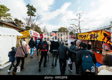 Le Japon, Kyoto, Fushimi Inari Taisha, nouvelle année. Des foules de gens se dirigeant vers le principal de torii et entrée de la fox le plus important lieu de culte au Japon. Route bordée de stands de nourriture. Les gens font leur première visite au sanctuaire de la nouvelle année. Banque D'Images