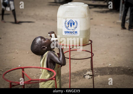 L'Ouganda. 26 mai, 2017. Un jeune enfant réfugié vu l'eau potable à partir d'un réservoir d'eau qui fournit de l'eau potable par l'UNCHR.Afin d'assurer l'approvisionnement en eau dans les différents camps de réfugiés, il faut 2 millions de litres d'eau par jour. 400 000 $ USD est nécessaire uniquement pour le transport de l'eau.Le nombre de réfugiés soudanais du sud qui ont franchi sa frontière a atteint un million. Ce pays d'Ouganda offre les réfugiés des conflits d'une carte d'identité et d'un terrain de 900mÂ² et le droit de commerce sur son territoire. Cependant, avec l'afflux d'environ 1 000 personnes par jour et le manque de financement Banque D'Images