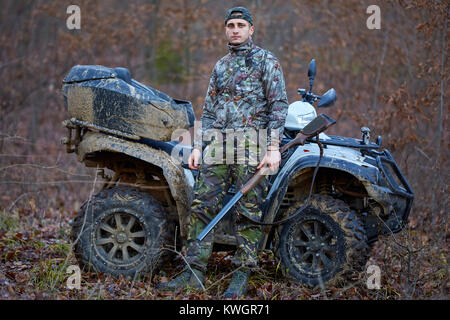 Jeune chasseur sur un quad à la recherche de jeu dans la forêt Banque D'Images