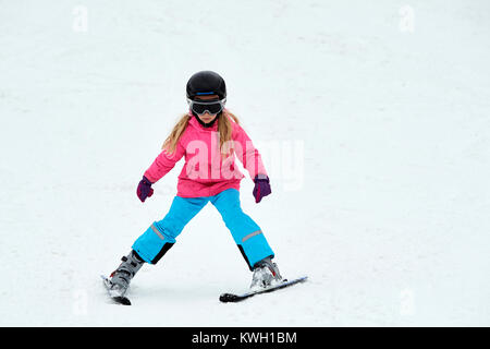 Enfant de ski dans les montagnes. Fille en costume coloré et casque de sécurité l'apprentissage du ski. Sport d'hiver pour les familles avec de jeunes enfants. Cours de ski pour enfants i Banque D'Images