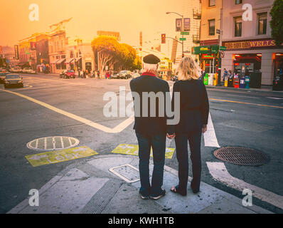 Deux amants matures se tenant par la main dans les rues de San Francisco au coucher du soleil, en Californie, aux États-Unis. Banque D'Images