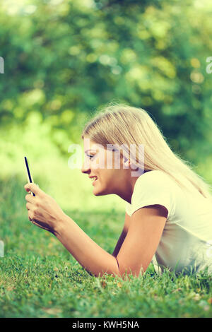 Woman using digital tablet in park Banque D'Images