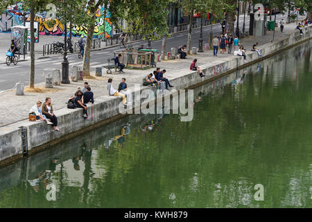 Des gens assis sur la rive du Canal Saint Martin à Paris. Banque D'Images