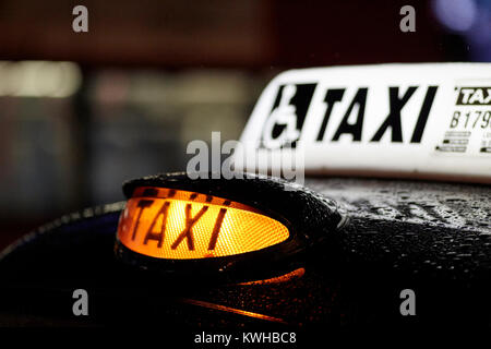 Taxi jaune pour voitures sur le toit de lumière la nuit dans la pluie de l'Irlande du Nord Belfast, Royaume-Uni Banque D'Images