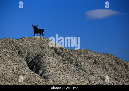 Taureau espagnol noir au sommet d'une colline silhouette sur un ciel bleu profond - classique Espagne. Banque D'Images