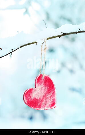Saint Valentin en forme de coeur, décorations rouge accroché sur la neige et d'arbres sur l'arrière-plan. Banque D'Images