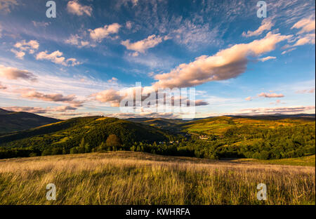 En pente gazonnée montagneux au coucher du soleil. beau paysage avec de magnifiques nuages sur les collines du massif des Carpates. Nyzhn emplacement Banque D'Images