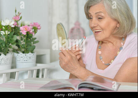 Portrait of a smiling young woman applying lipstick Banque D'Images