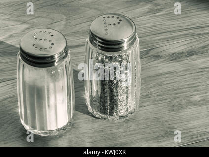 Close up de salière et poivrière en verre ou des pots de sel et de poivre sur une table en bois . Banque D'Images