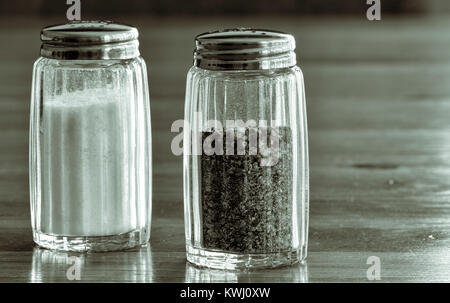 Close up de salière et poivrière en verre ou des pots de sel et de poivre sur une table en bois . Banque D'Images