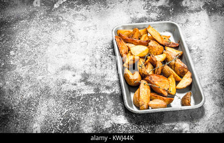 Les pommes sur une plaque à pâtisserie avec épices et herbes. Sur un fond rustique. Banque D'Images