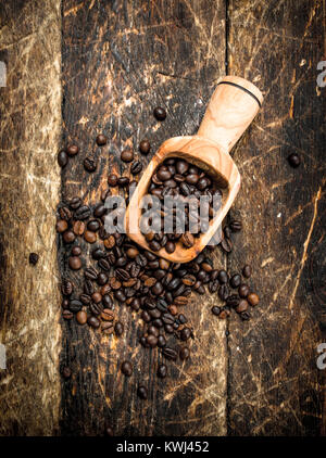 Grains de café d'un scoop. Sur un fond de bois. Banque D'Images
