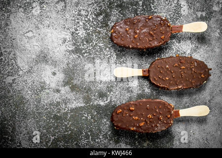 La crème glacée fraîche sur un bâtonnet dans le chocolat avec des écrous. Sur un fond rustique. Banque D'Images