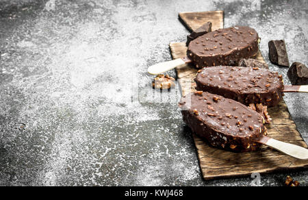 La crème glacée fraîche sur un bâtonnet dans le chocolat avec des écrous. Sur un fond rustique. Banque D'Images