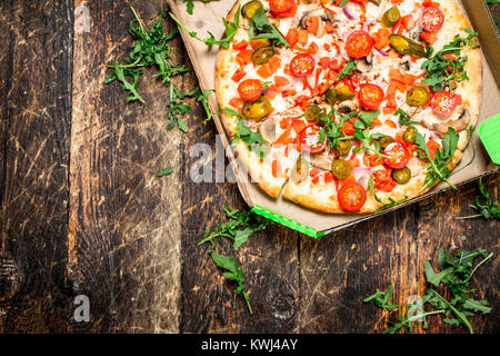 Pizza aux tomates fraîches et des verts. On a wooden background Banque D'Images