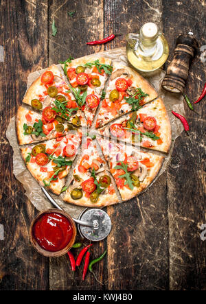 Pizza aux tomates fraîches et des verts. On a wooden background Banque D'Images