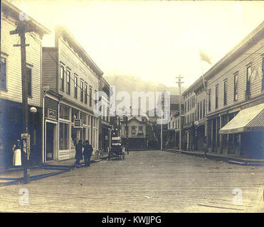 Cette photographie d’environ 1901 montre une scène de rue à Juneau, en Alaska, capturant des bâtiments en bois, des piétons et l’environnement urbain du début du XXe siècle dans la région de la capitale de l’Alaska. Banque D'Images