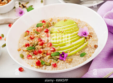 Porridge d'avoine sains et savoureux avec des pommes, des grenades et des écrous. Petit déjeuner sain. Alimentaire de remise en forme. Une bonne nutrition Banque D'Images