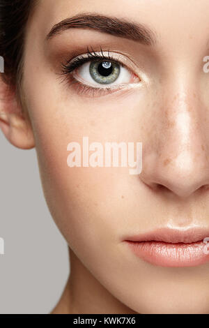 Closeup macro portrait de visage de femme. Femme humaine face demi-journée avec un miroir de beauté. Fille avec une peau parfaite et des taches de rousseur. Banque D'Images