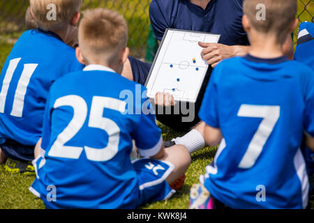 Enfants Coaching Soccer. L'équipe de football avec l'entraîneur au stade. Les garçons à l'écoute des instructions de l'entraîneur avant la compétition. Coach de l'équipe donnant à l'aide de parler Banque D'Images