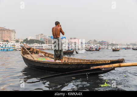 Dhaka, Bangladesh : Boatman lave lui-même sur un bateau en bois en bas de la rivière Buriganga Ganmges dans Old Dhaka. Un grand bac blanc est dans l'arrière-plan Banque D'Images