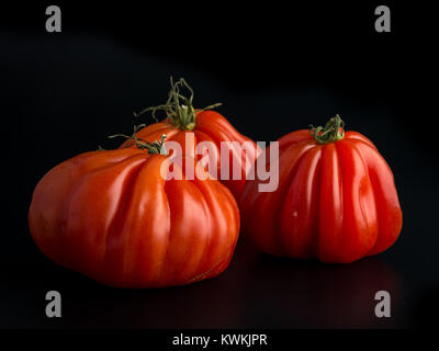 Trois grosses tomates Beefsteak sur fond noir Banque D'Images