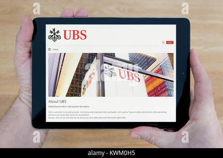 Un homme regarde le site web de la banque UBS sur son iPad tablet, sur une table en bois page contexte (usage éditorial uniquement) Banque D'Images