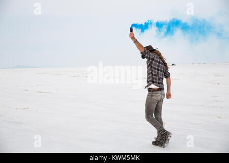 Side view of man holding bombe fumigène en se tenant sur le Bonneville Salt Flats against sky Banque D'Images
