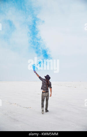 Vue arrière de l'homme tenant une bombe de fumée en se tenant sur le Bonneville Salt Flats against sky Banque D'Images
