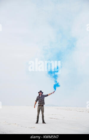 Portrait d'homme tenant une bombe de fumée en se tenant sur le Bonneville Salt Flats against sky Banque D'Images