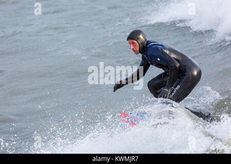 Bournemouth, Dorset, England UK. 4 janvier, 2018. Météo France : surfer une vague profitant du surf sur un jour de vent à la plage de Bournemouth, que les surfeurs profiter de la vent et de grosses vagues. Banque D'Images