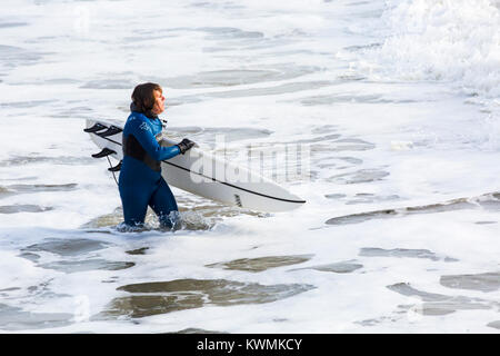 Bournemouth, Dorset, England UK. 4 janvier, 2018. Météo France : surfer holding surfboard, la position dans la mer pour profiter du surf sur un jour de vent à la plage de Bournemouth, que les surfeurs profiter de la vent et de grosses vagues. Banque D'Images
