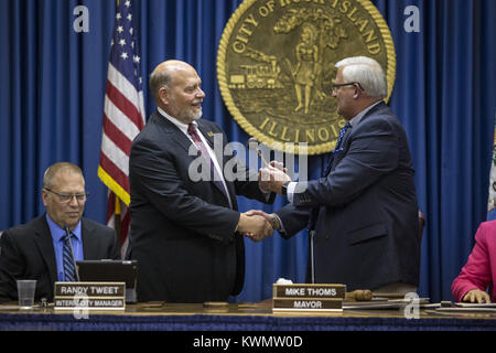 Rock Island, Iowa, États-Unis. 1er mai 2017. Ancien maire Dennis Pauley, droite, serre la main avec Mayor-Elect Mike Thoms comme il lui tend un marteau et abandonne son siège dans les chambres de l'Hôtel de Ville de Rock Island, le lundi 1 mai 2017. Credit : Andy Abeyta, Quad-City Times/Quad-City Times/ZUMA/Alamy Fil Live News Banque D'Images