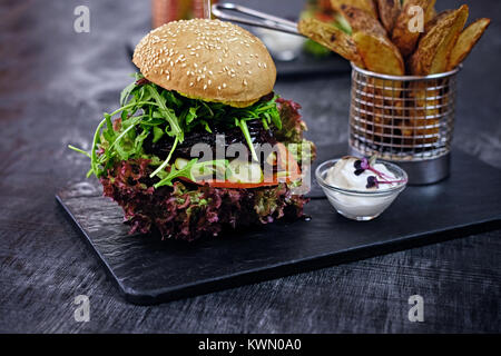 Burger, frites avec salade sur une table. Banque D'Images