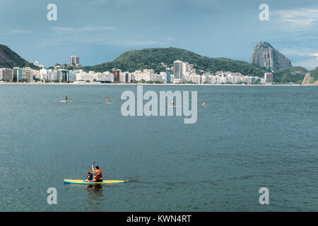 Rio de Janeiro, Brésil - janvier 3rd, 2018 : Père et fille faire du Stand Up Paddle sur la plage de Copacabana, Rio de Janeiro, Brésil avec des bâtiments et S Banque D'Images