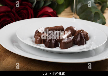 Assiette de chocolats close up avec des roses en arrière-plan Banque D'Images