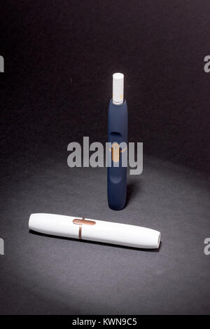 Les cigarettes électroniques plus récents, chauffage système IQOS, fumeurs de tabac, blanc et bleu foncé sur fond noir isolé de l'appareil Banque D'Images
