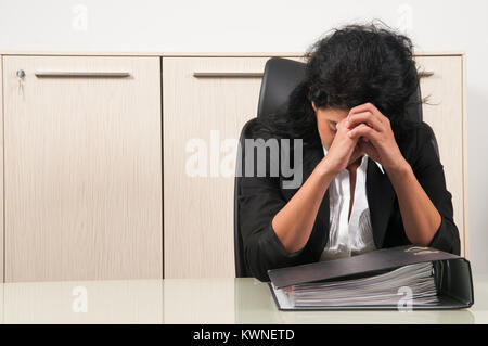 Femme d'affaires a souligné la tête dans les mains était assis dans son bureau Banque D'Images